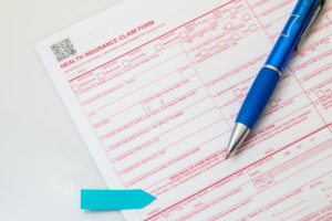 Health insurance claim form with pen on white background.