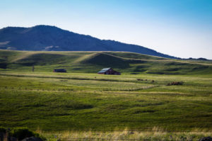 Landscape image of barn, cattle ranch, fence and hills