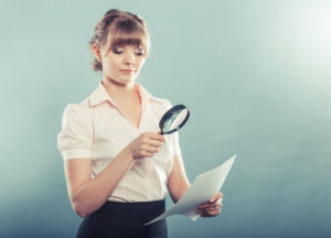 Woman uses magnifying glass to check paper